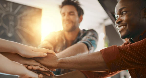 People joining their hands together in a gesture of teamwork and unity.