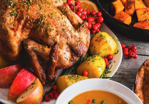 A roasted chicken with potatoes and apples, a bowl of soup with garnish, and a skillet of roasted squash sit on a rustic table.