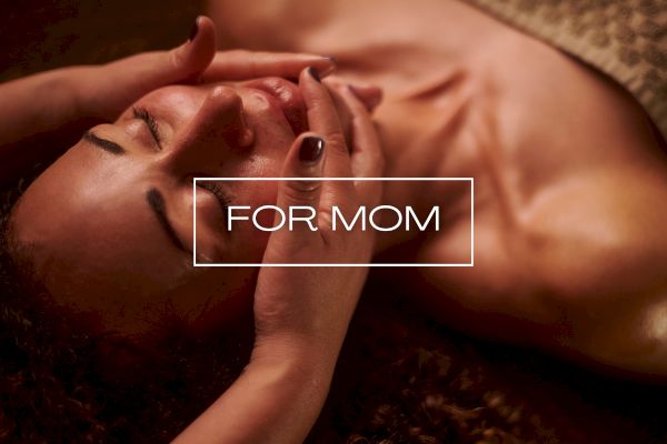 A person receiving a relaxing face massage, with the words "For Mom" overlayed at the center of the image.