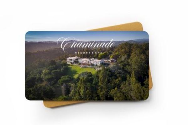 An image of a card with a photograph of Chaminade Resort & Spa, showing a resort amidst a forested area. A light brown envelope is underneath the card.