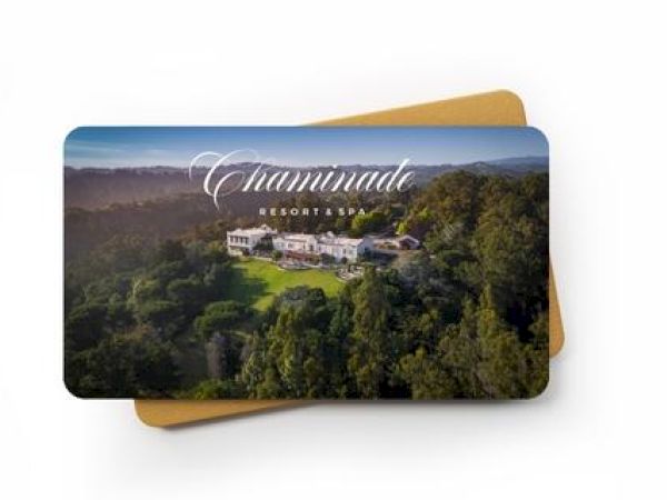 An image of a card with a photograph of Chaminade Resort & Spa, showing a resort amidst a forested area. A light brown envelope is underneath the card.
