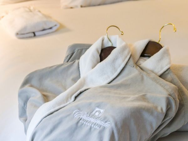 A close-up of two bathrobes and towels on a hotel bed, with gentle lighting creating a cozy atmosphere.