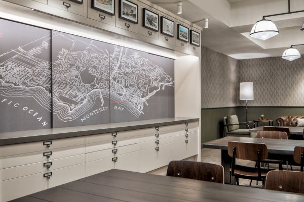 The image shows a room with a large map of Monterey Bay on the wall, surrounded by tables, chairs, and modern lighting fixtures.