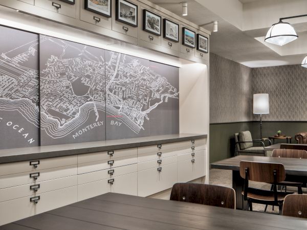 The image shows a room with a large map of Monterey Bay on the wall, surrounded by tables, chairs, and modern lighting fixtures.