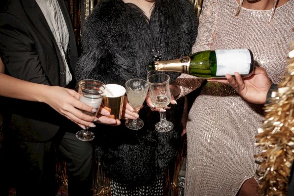 People dressed elegantly are pouring champagne into glasses, ready to celebrate.