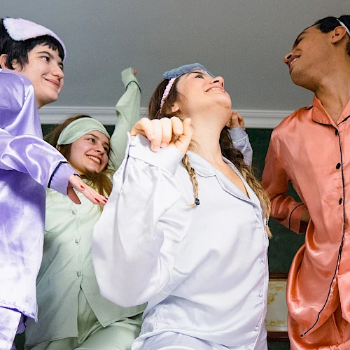 Four people in colorful pajamas are happily dancing together in a room, looking joyful and lively.