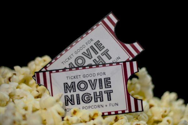 The image shows two "Movie Night" tickets on a pile of popcorn, suggesting an event of films, popcorn, and fun.