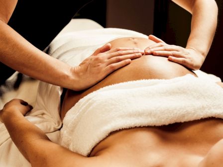 A person receiving a massage with hands on their back, covered by a white towel.
