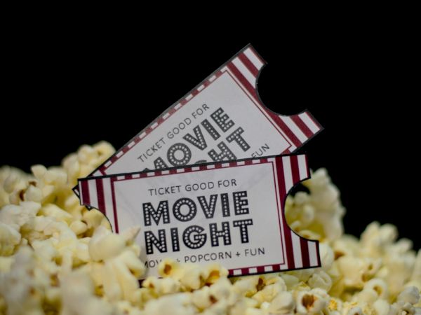 The image shows two "Movie Night" tickets on a pile of popcorn, suggesting an event of films, popcorn, and fun.