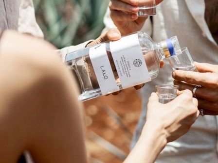 People pouring shots from a bottle and taking drinks together at a casual outdoor gathering.