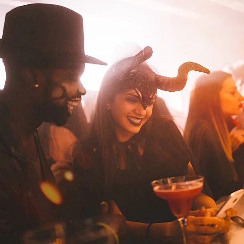 People in costumes enjoying drinks at a party, with a festive and lively atmosphere.