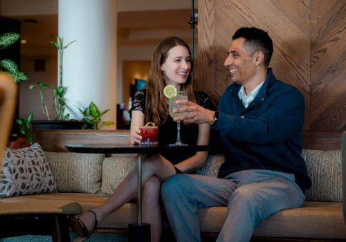 Two friends relaxing at a cozy bar, sharing drinks and smiles while chatting warmly.