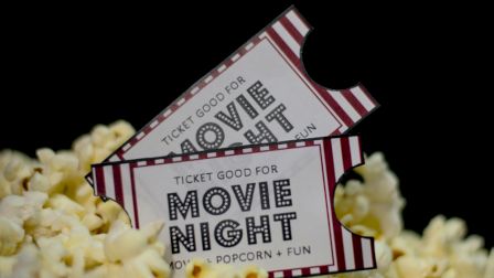 The image shows two "Movie Night" tickets on a pile of popcorn, suggesting an event of films, popcorn, and fun.